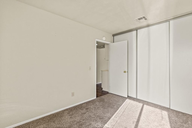 unfurnished bedroom featuring dark carpet and a closet