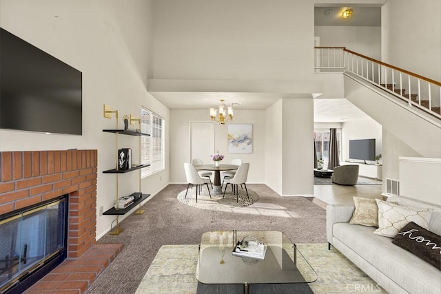 living room featuring a brick fireplace, a towering ceiling, a notable chandelier, and carpet