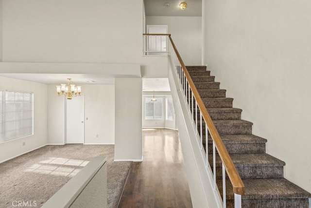 stairway with hardwood / wood-style flooring and a towering ceiling