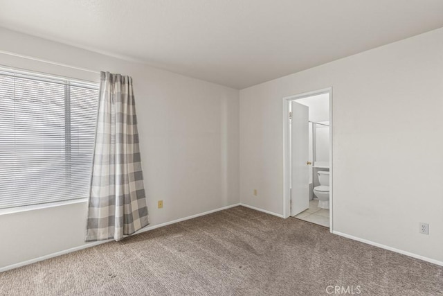 unfurnished bedroom featuring light colored carpet and ensuite bathroom