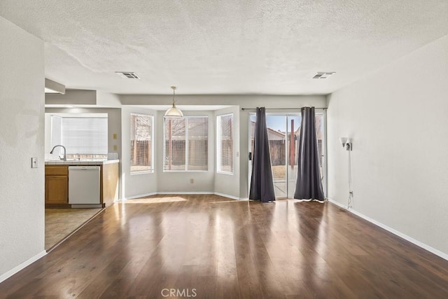 unfurnished living room featuring hardwood / wood-style flooring, plenty of natural light, sink, and a textured ceiling