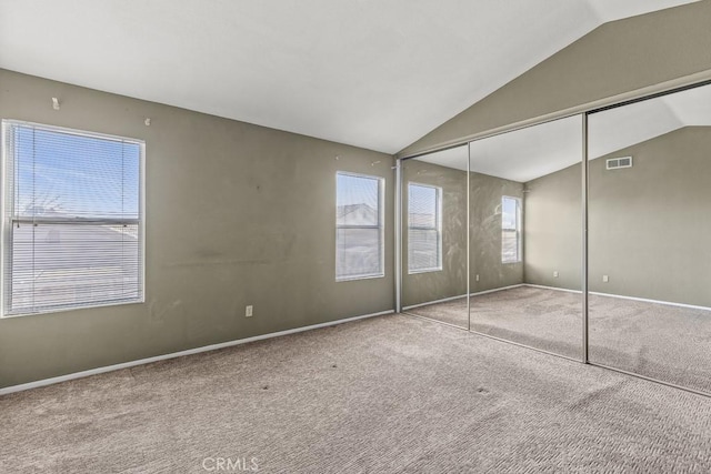 unfurnished bedroom featuring vaulted ceiling, carpet floors, and a closet