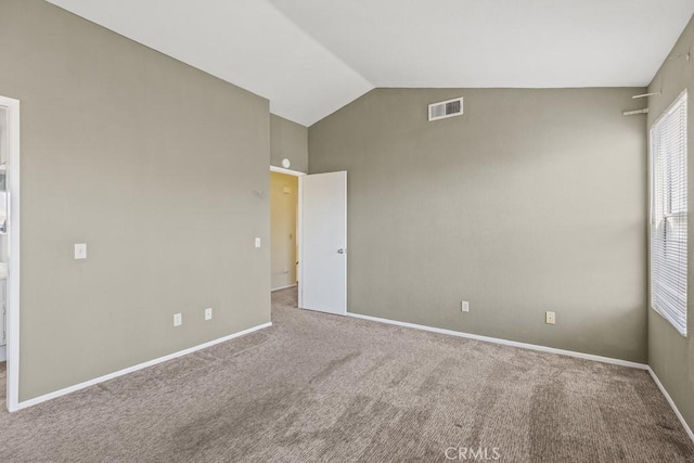 carpeted empty room featuring lofted ceiling