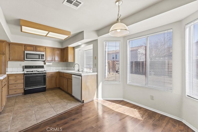 kitchen with hanging light fixtures, a wealth of natural light, stainless steel appliances, and sink