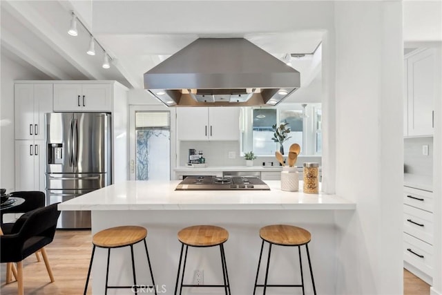 kitchen featuring white cabinetry, island exhaust hood, stainless steel appliances, and a breakfast bar