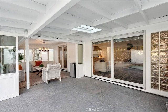 unfurnished sunroom featuring a chandelier, beam ceiling, and a skylight