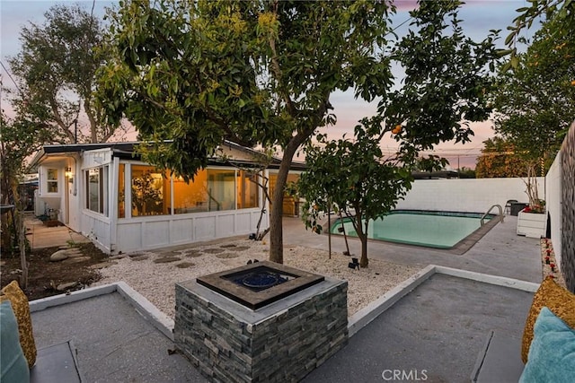 pool at dusk with a patio area and an outdoor fire pit