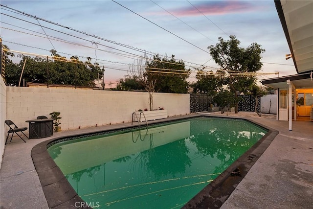 pool at dusk featuring a patio area