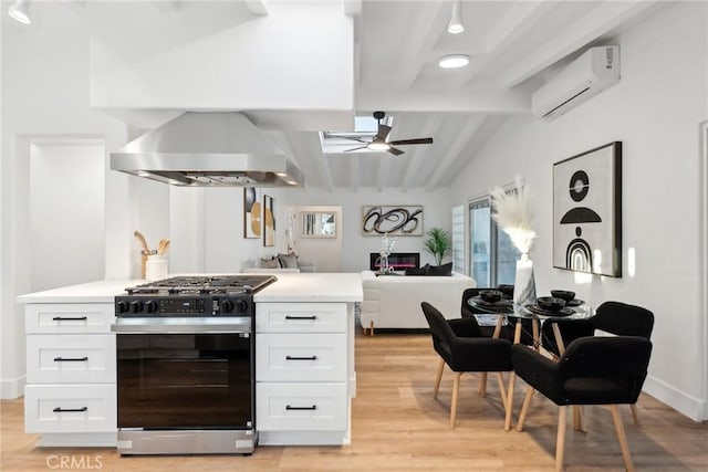 kitchen with vaulted ceiling with beams, gas range, white cabinetry, a wall mounted AC, and ceiling fan