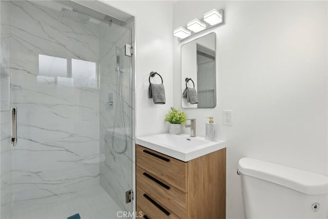 bathroom featuring a shower with door, vanity, and toilet