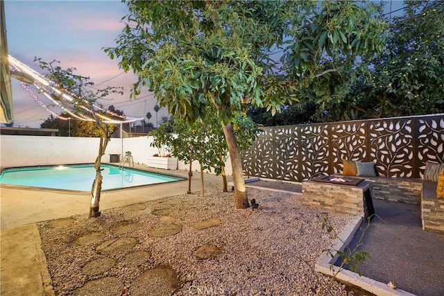 pool at dusk featuring an outdoor fire pit and a patio area