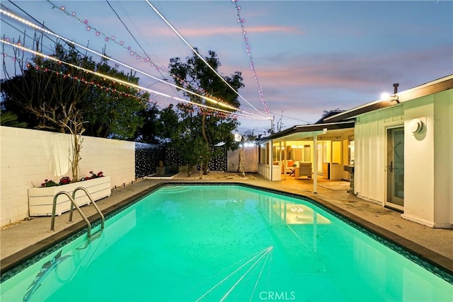 pool at dusk featuring an outdoor living space and a patio