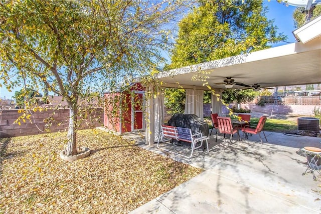 view of yard featuring ceiling fan, a storage shed, and a patio