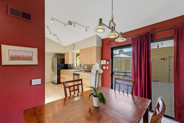 dining room with sink, light tile patterned floors, and vaulted ceiling