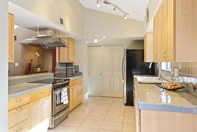 kitchen with light tile patterned floors, light brown cabinets, stainless steel appliances, tile counters, and ventilation hood