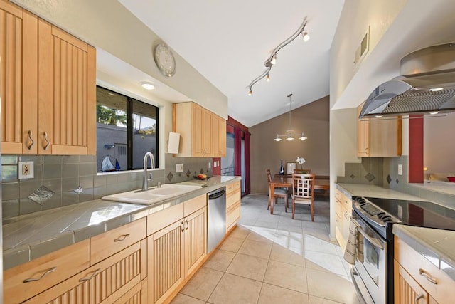 kitchen with lofted ceiling, stainless steel appliances, sink, backsplash, and tile countertops