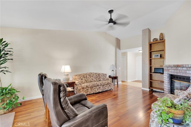 living room featuring ceiling fan, hardwood / wood-style flooring, lofted ceiling, and a fireplace