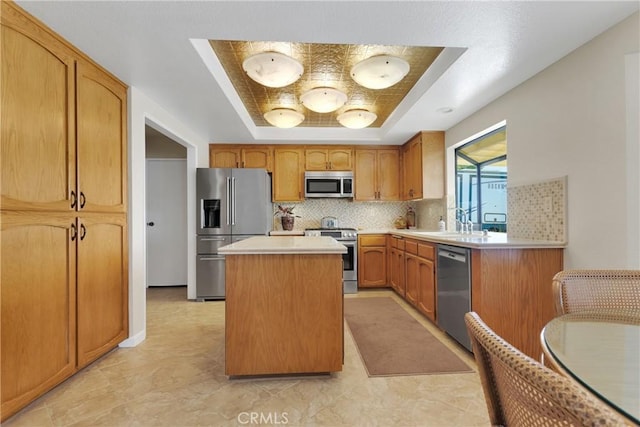 kitchen featuring a kitchen island, a raised ceiling, decorative backsplash, sink, and stainless steel appliances