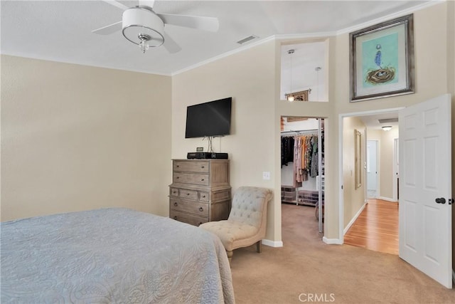 carpeted bedroom featuring ceiling fan, a walk in closet, a closet, and ornamental molding