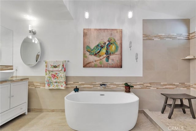 bathroom with tile walls, a bathtub, and vanity