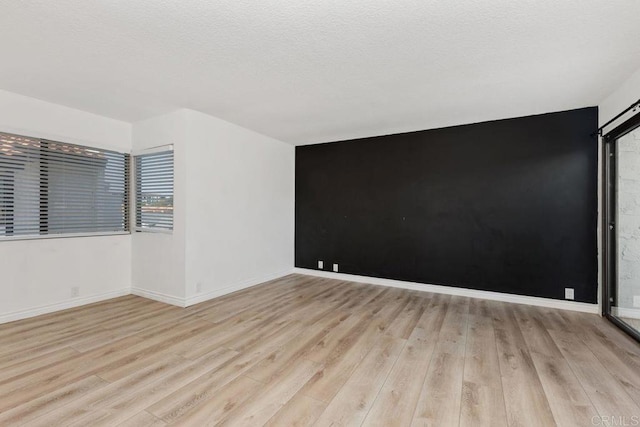 empty room featuring a textured ceiling and light wood-type flooring