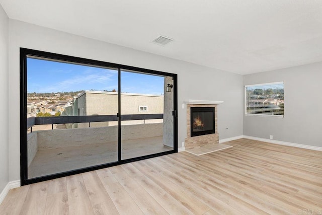 unfurnished living room with light hardwood / wood-style flooring and a tiled fireplace