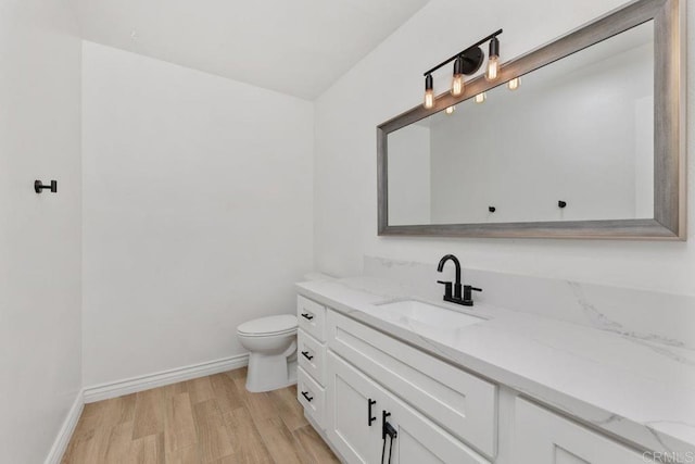 bathroom with toilet, hardwood / wood-style floors, and vanity