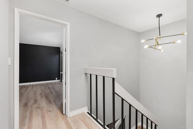 stairway with wood-type flooring and a notable chandelier