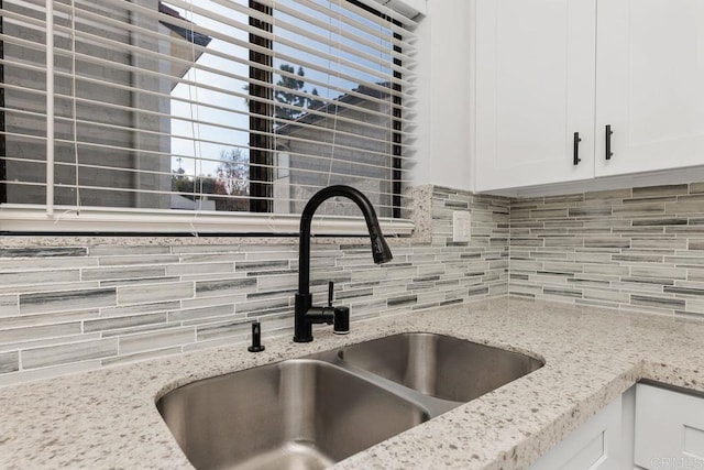 room details with tasteful backsplash, sink, and white cabinetry