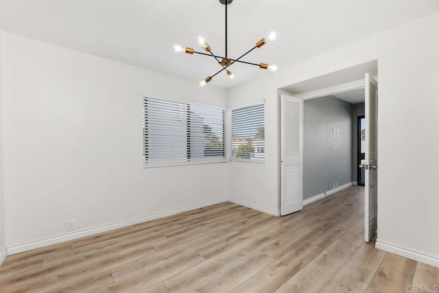 empty room featuring light hardwood / wood-style floors and a notable chandelier