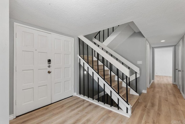 foyer entrance with light hardwood / wood-style floors and a textured ceiling