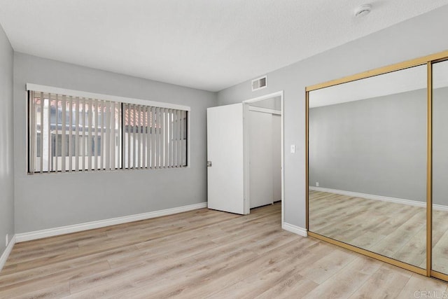 unfurnished bedroom featuring a closet and light hardwood / wood-style floors