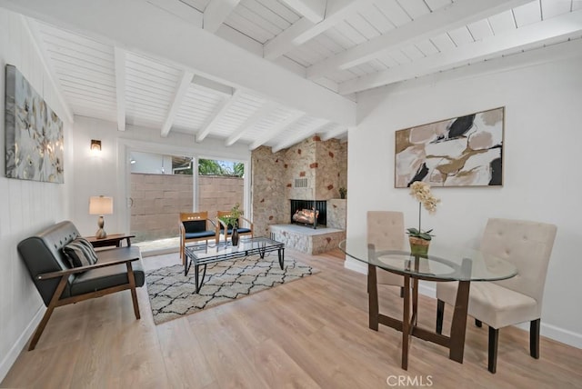 living room with light wood-type flooring, a fireplace, and beamed ceiling