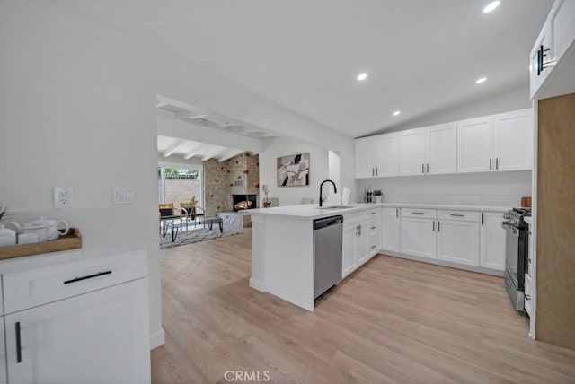 kitchen featuring white cabinetry, kitchen peninsula, appliances with stainless steel finishes, a fireplace, and sink