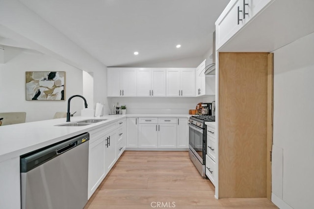 kitchen featuring vaulted ceiling, sink, light wood-type flooring, stainless steel appliances, and white cabinets