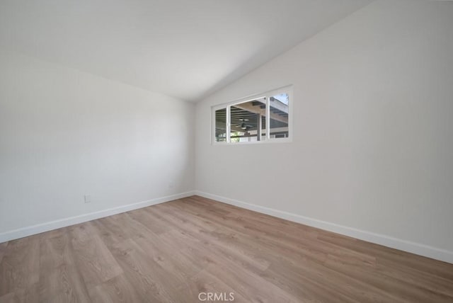 unfurnished room with light wood-type flooring and vaulted ceiling