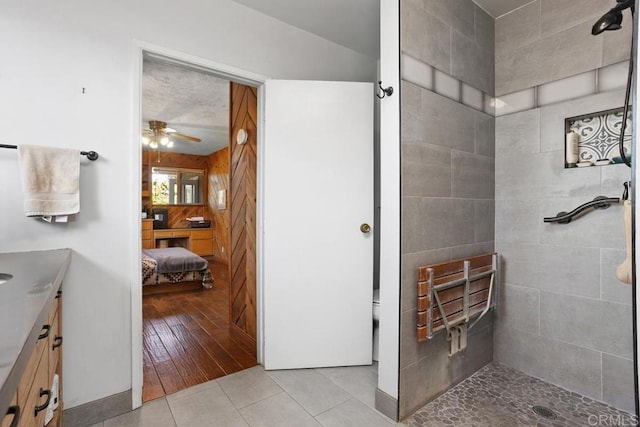 bathroom featuring ceiling fan, vanity, tile patterned floors, tiled shower, and a textured ceiling