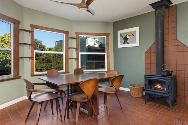 tiled dining space with ceiling fan and a wood stove