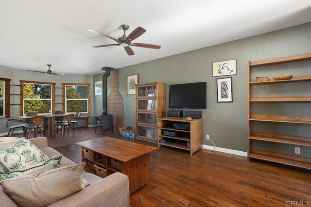 living room with dark wood-type flooring, a wood stove, and ceiling fan