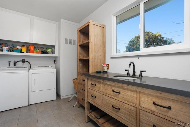 laundry room with light tile patterned floors, washing machine and dryer, sink, and cabinets