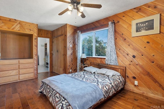 bedroom featuring ceiling fan, dark wood-type flooring, and wood walls