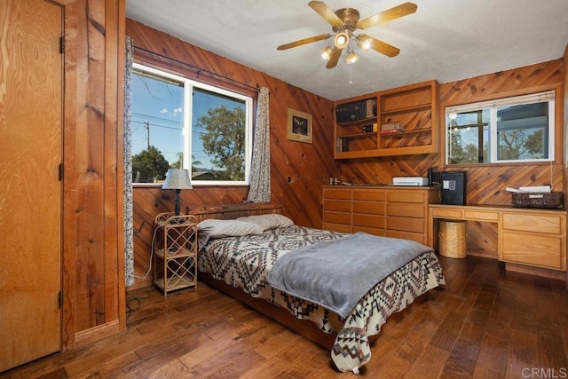 bedroom featuring dark wood-type flooring, ceiling fan, and wooden walls