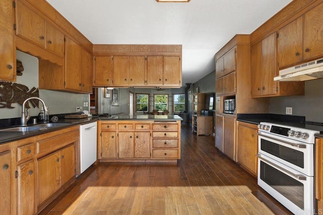 kitchen with white appliances, sink, dark hardwood / wood-style floors, kitchen peninsula, and vaulted ceiling