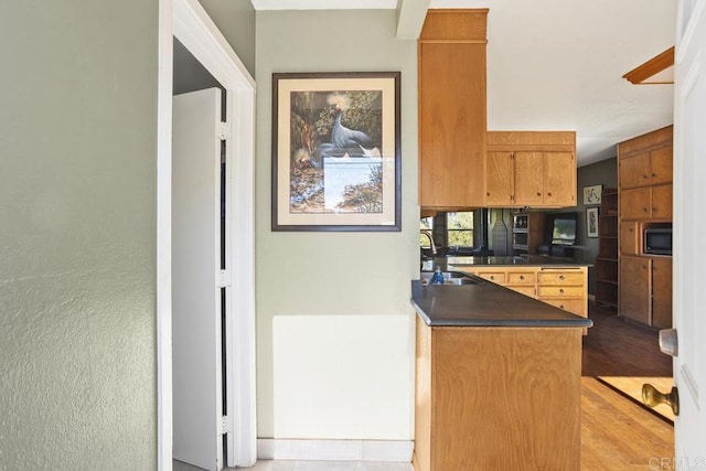 kitchen featuring kitchen peninsula, built in microwave, and sink