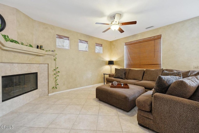 living room featuring ceiling fan, light tile patterned floors, and a tiled fireplace