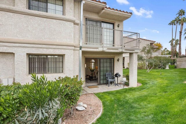 doorway to property featuring a lawn, a balcony, and a patio