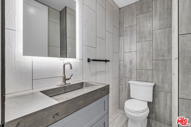 bathroom with tile walls, toilet, and vanity