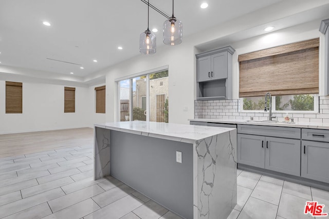 kitchen featuring light stone countertops, a kitchen island, a healthy amount of sunlight, and sink