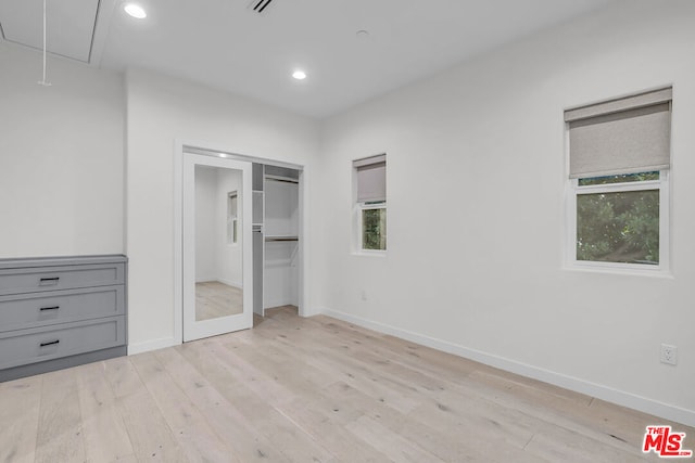 unfurnished bedroom featuring a closet, multiple windows, and light hardwood / wood-style flooring