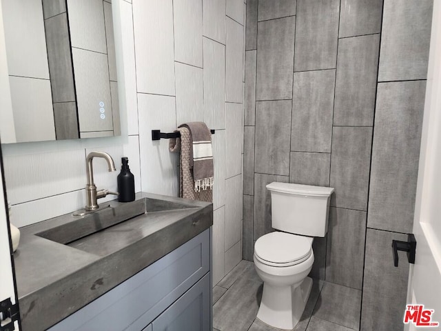 bathroom with tile walls, toilet, and vanity